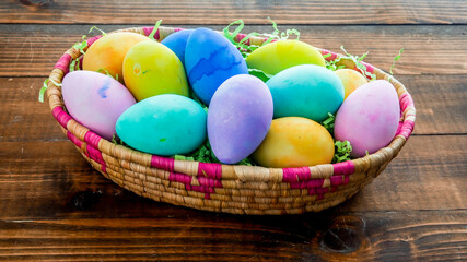 Colorful Easter eggs inside bucket on wooden table