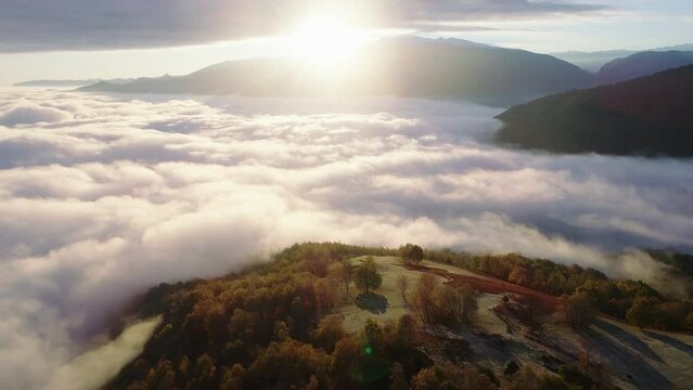Flying over a hill towards an ocean of clouds covering the valley below