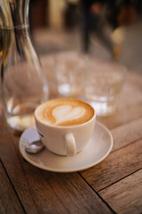 Hot art Latte Coffee in a cup on wooden table and Coffee shop blur background with bokeh image