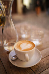 Hot art Latte Coffee in a cup on wooden table and Coffee shop blur background with bokeh image