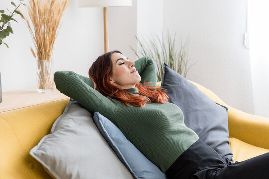 Dreamy woman resting on sofa in living room