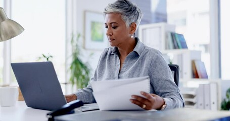 Laptop, documents and review with a business woman at work in her office for a proposal or report. Computer, reading and paperwork with a serious female employee busy working on a research project - Powered by Adobe