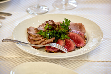 Appetizer plate with a meat selection. Sliced baked ham. Table setting in a restaurant