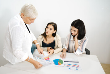 Aged businesswoman meeting with colleague teamwork women talking, planning business strategy for collaboration. Professional female mature manager working in office discussing startup project document