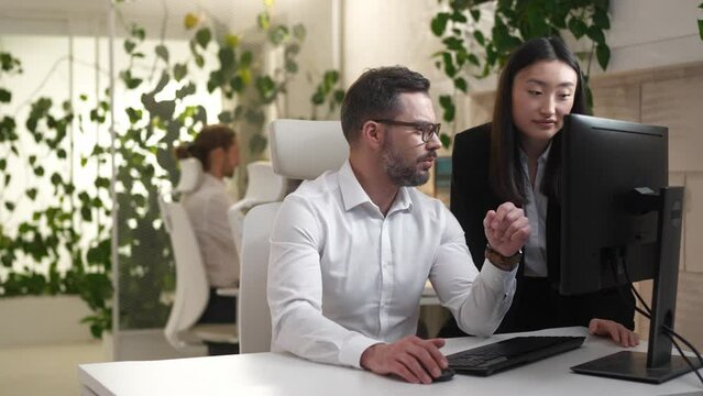 Portrait of two focused office workers consulting helping asking for advice. Attractive young female manager and adult professional developer talking in modern IT office company. Colleagues concept.
