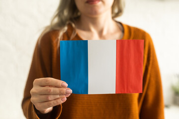 close up hand holding french flag on studio isolated white background