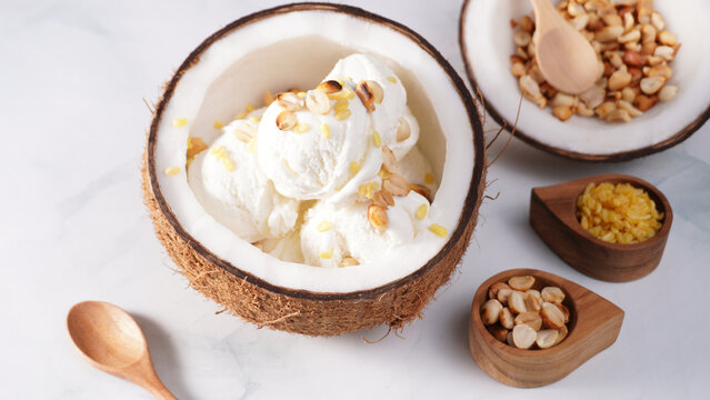 Coconut ice cream topped with roasted peanuts in a coconut shell