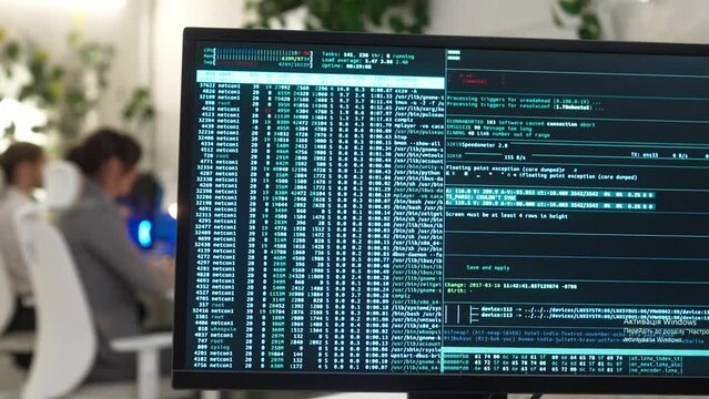 Monitor of computer in modern IT company office with big database code with young successful female and male focused developers coding on computers wearing smart style clothes.