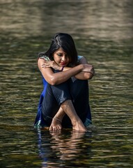 A beautiful young girl sitting in a river water and thinking something. syhet, Bangladesh