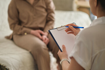 patient makes progress towards healing and recovery as she talks with her therapist about her struggles. psychologist takes notes during the therapy session to help her patient