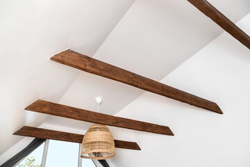 Stained brown decorative wooden beams in home living room white color ceiling. Nice modern contrast...