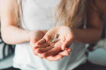 Close up two vitamin pills on the palm of unrecognizable woman hand