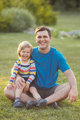 Fototapeta premium Smiling father with son have fun and walking in garden. Happy family portrait.