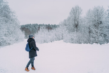 Fototapeta na wymiar A man with a blue backpack in a snowy park