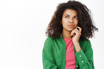 Portrait of girl with thoughtful face, thinking of something, pondering, has an idea, stands perplexed against white background