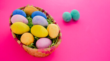 Fototapeta na wymiar Colorful bright Easter eggs inside basket on pink background