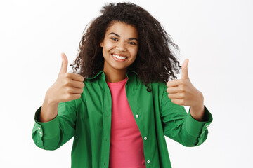Smiling Black woman shows thumbs up, like and recommend smth, say yes, nod in approval