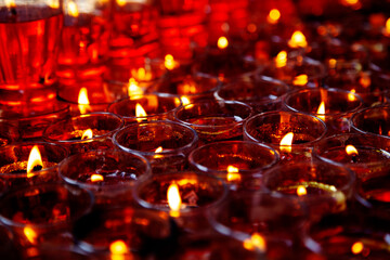 Close-up photo of a lot of red candles in glasses burning in a Chinese Taoist shrine at night. The...