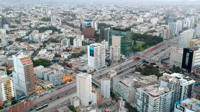 Drone revelation shot showing the city of Lima, a principal avenue and buildings in a cloudy day