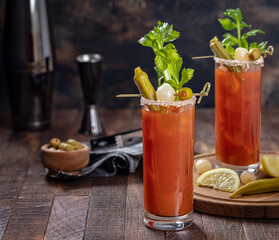 Bloody mary cocktail with garnishes on dark wooden background