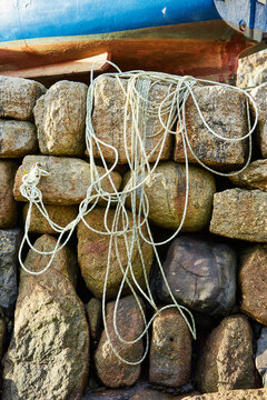 Mousehole, Cornwall, UK - Port wall with rope and fishing boat on top at low tide