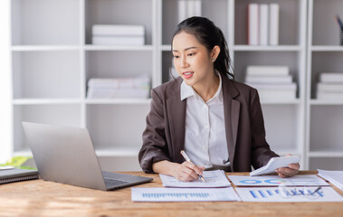 Fototapeta premium Business Asian woman working at office with documents on her desk, calculator to calculate planning analyzing the financial report, business plan investment, finance analysis concept