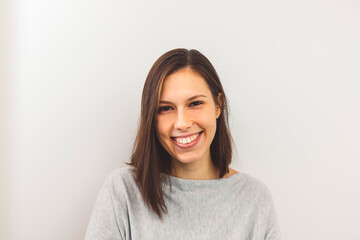 Obraz premium Waist up portrait of cheerful young woman with shoulder length hair and big white smile on white background 