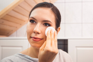 Waist up close up portrait of a young woman removing make up in her bathroom at night 