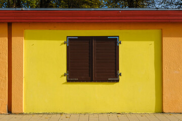 Fototapeta na wymiar Gelbe Fassade mit geschlossenem Braunem Fensterladen, Schleswig-Holstein, Deutschland