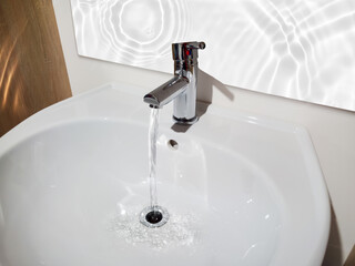 flowing water jet from faucet into the vanity basin, symbolic concept for consumption of water resource