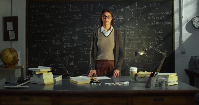 Zoom in: Portrait of Young Female Teacher in University Classroom Standing In Front of Blackboard with Mathematic Formulas. Science Female Researcher in College Library, Looking at Camera Seriously