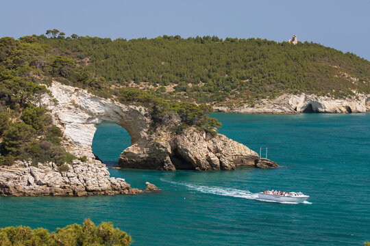Boat passing under Arco di San Felice arch with Torre Gattarella behind, Vieste, Gargano peninsula, Foggia province, Puglia
