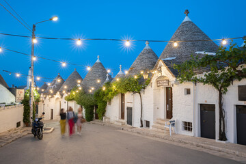 Whitewashed trulli houses along Via Monte San Michele street in the old town lit up at dusk, Alberobello, UNESCO World Heritage Site, Puglia