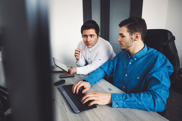 Two young caucasian programmers working on desktop computers in the office developing a new video game 