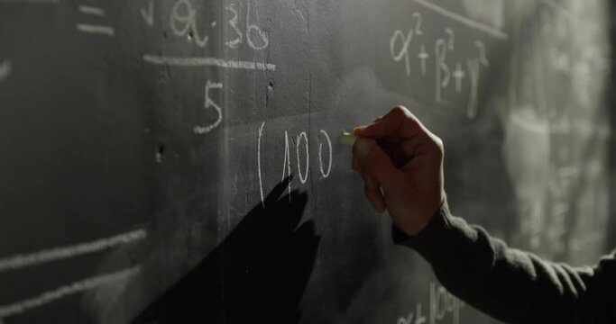 Close Up on the Hand of a Female University Teacher Writing a Mathematics Formula on a Blackboard with White Chalk. College Science Professor Teaching, Solving a Complex Equation