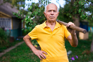 Naklejka na ściany i meble Old man standing in backyard with shovel in hand