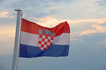 Flag of Croatia on the boat, blowing in the wind. Sea and sunset sky in the background. Selective focus.