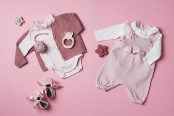 Set of pink clothes and accessories fot newborn girl. Toys, bodysuit, romper, knitted cardigan, shoes, bib on pastel backgroundd. Mock up tor text. Baby shower concept. Flat lay, top view