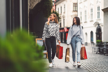 Two young women on a shopping spree in the city center, walking around with paper shopping bags in their hands 