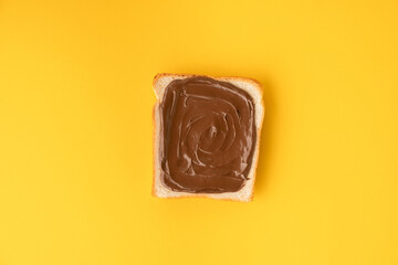 Top view of white toast bread with chocolate hazelnut spread on the yellow background. Morning breakfast concept. Food mockup with copy space for a free text. Flat lay.