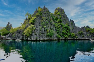 Majestic rocks in Coron, Palawan in the Philippines that are overgrown with shrubs and rise out of the water.