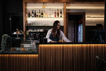 Waitress preparing coffee behind bar counter in cafe.