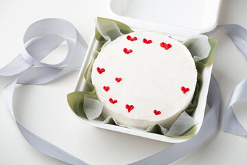 Small traditional Korean style bento cake with white cream cheese frosting decorated with red cream...