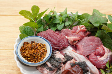 Fresh raw beef and Thai local herbal vegetables, prepare for cooking. Concept, food ingredient. Tradiotnal weird food. Popular menu in northern of Thailand.  Local food. Food ingredients to cook Larb.