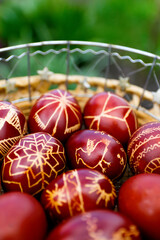 Closeup of basket of colored red eggs, Easter holiday concept. Modern painted easter eggs. Collection of pysanka or krashanka. Vertical. Out of focus