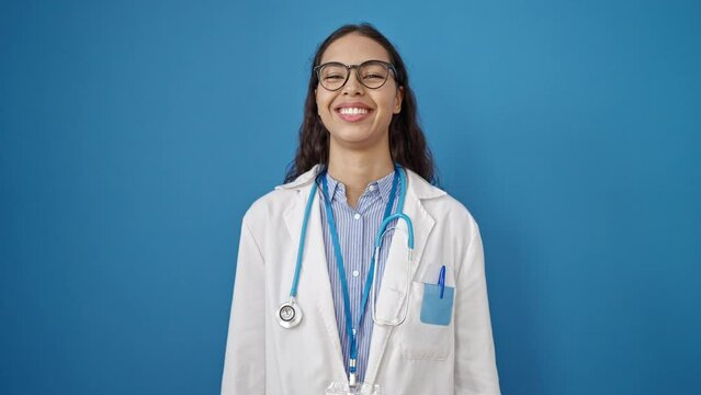 Young beautiful hispanic woman doctor smiling confident standing over isolated blue background