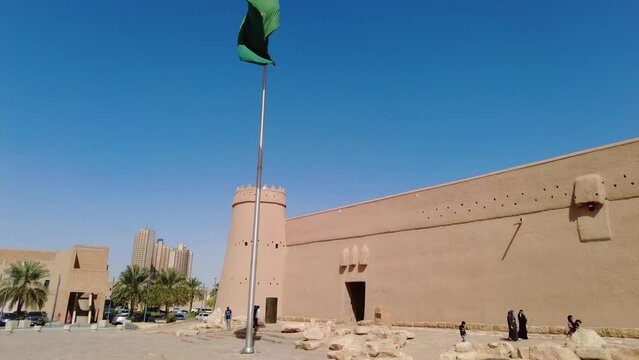 Riyadh, Saudi Arabia: Saudi national flag flies above the famous Masmak fort in Riyadh old town in Saudi Arabia capital city on a sunny day. Shot with a tilt down motion