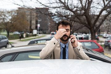 Young nervous business man standing by his car after working hours talking on the phone arguing...