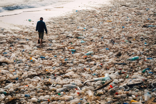 A beach with a mountain of plastic garbage scattered along the entire coastline, in the background a tourist trying to get to the ocean, the sea. The concept of an ecological disaster. Generative ai