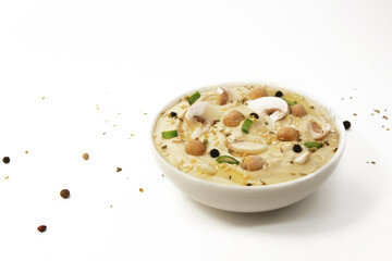 Hummus with mushrooms on a white background in a plate topped with chickpeas and sesame seeds, onion, oil and spices. Culinary and food menu photo